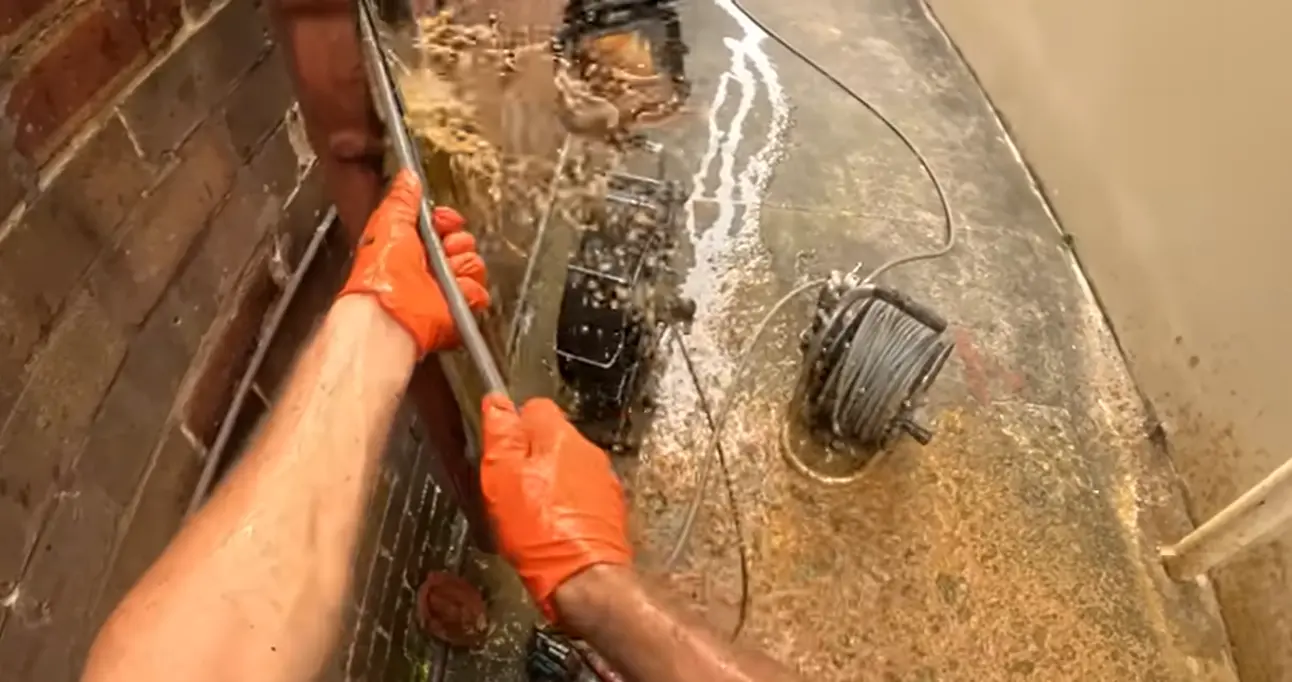 Professional drain cleaning in Fort Collins — technician using motorized cable to clear a kitchen drain